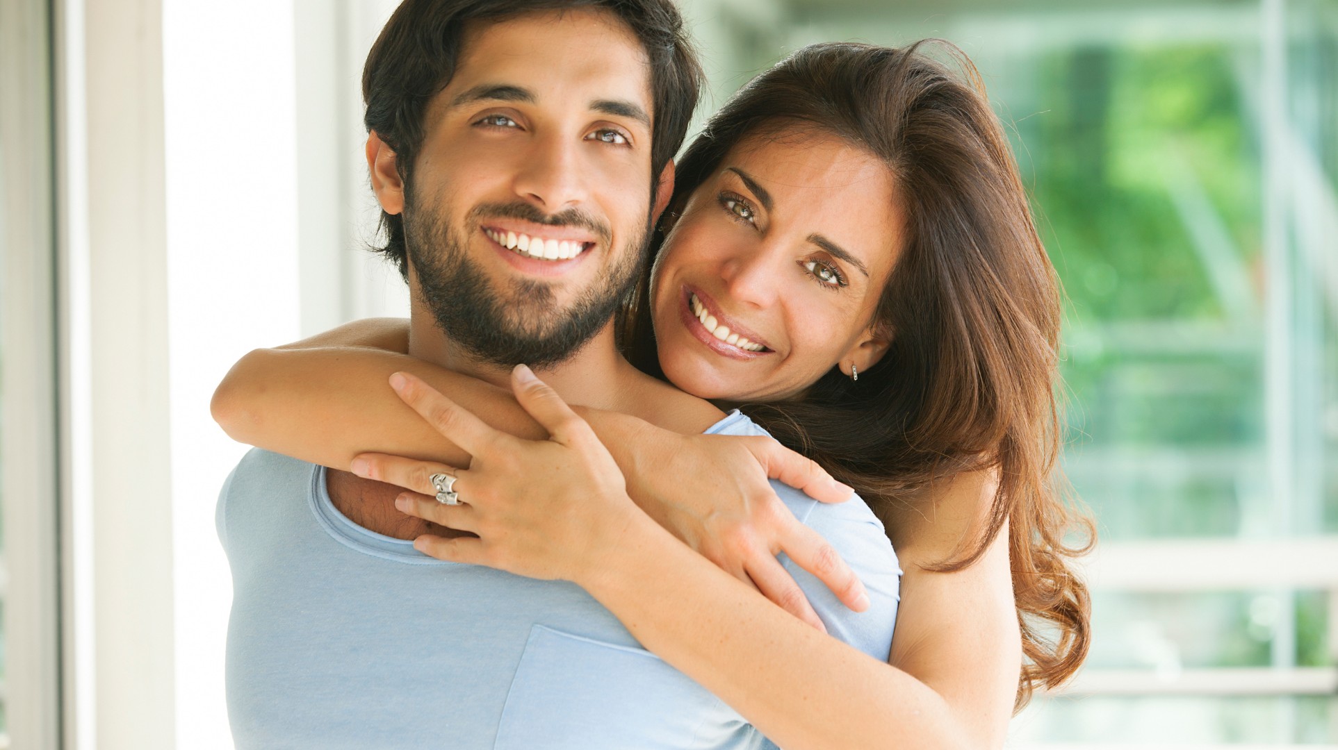 man and woman facing each other while smiling at the beach